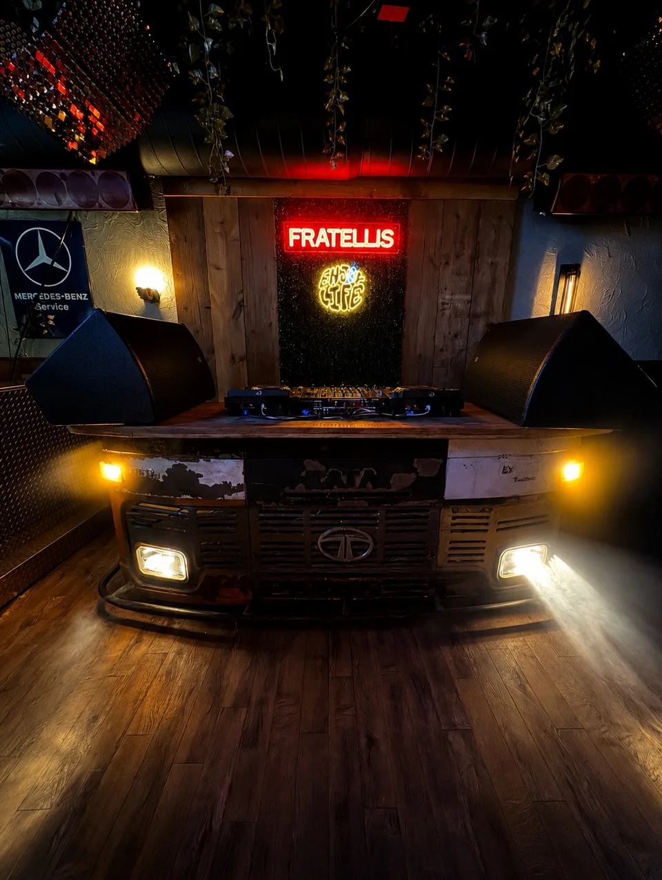 Fratelli’s DJ booth built into a vintage Tata bus front, beneath the red neon sign
