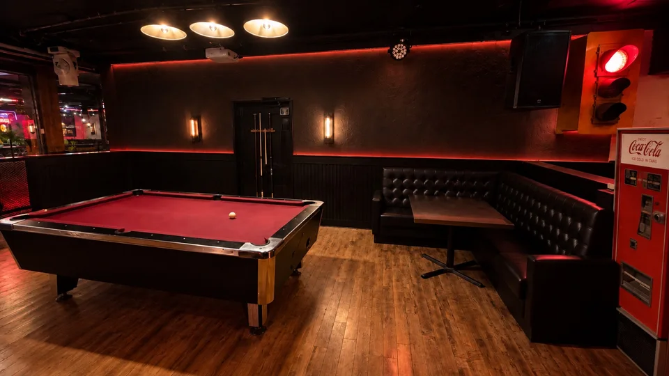 The lounge at Fratelli’s, with leather seating, warm wood floors and a red pool table